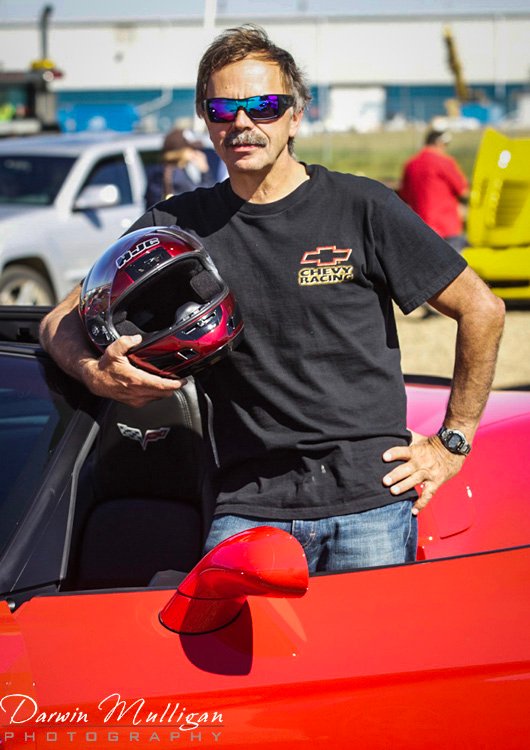 Darwin portrait with race car helmet and his Corvette
